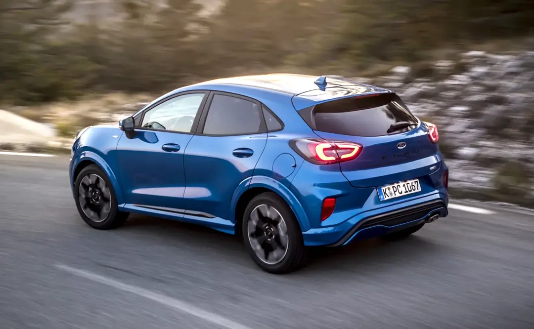 Ford Puma ST-Line in Blau fährt auf einer Straße bei Sonnenuntergang.