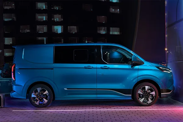 Seitliche Ansicht des Ford Transit Custom Doppelkabine LKW in Blau auf einem Parkplatz bei Nacht.