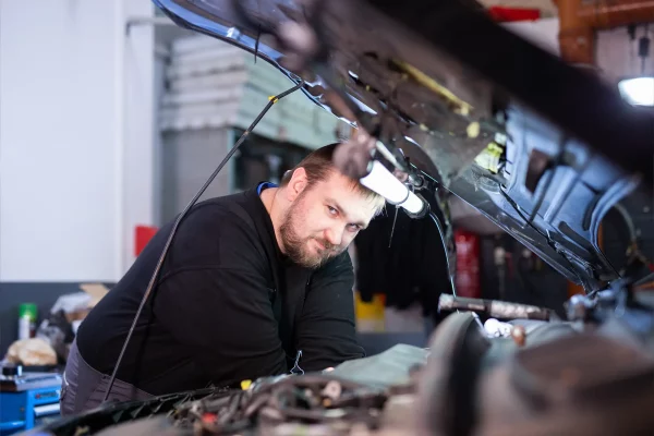 Kfz-Mechatroniker beugt sich über den Motorraum eines Fahrzeugs in der Werkstatt des Autohaus Hempel in Braunschweig.