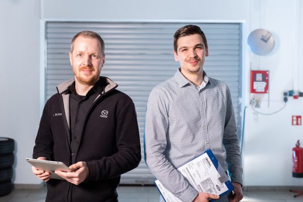 Zwei Serviceberater mit Klemmbrett stehen in der Direktannahme des Autohaus Hempel in Braunschweig.