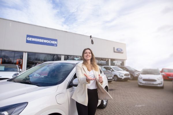 Kundin freut sich über ihrem neuen Ford Kuga und wirft ihre Autoschlüssel vor Freude in die Luft.