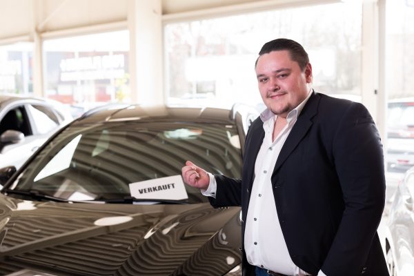 Mitarbeiter des Autohauses Hempel in Braunschweig vor einem verkauften Ford-Fahrzeug im Ford Showroom.