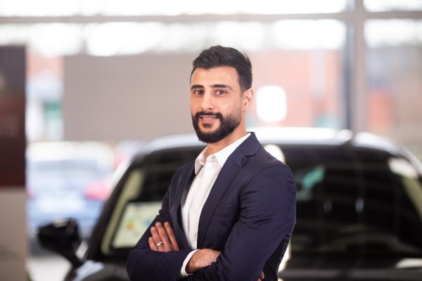 Junger Mitarbeiter steht im Showroom des Autohauses Hempel in Braunschweig und lächelt freundlich.