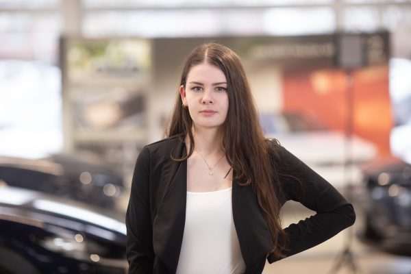 Junge Mitarbeiterin des Ford Autohaus Hempel in Braunschweig steht im Showroom und lächelt in die Kamera.