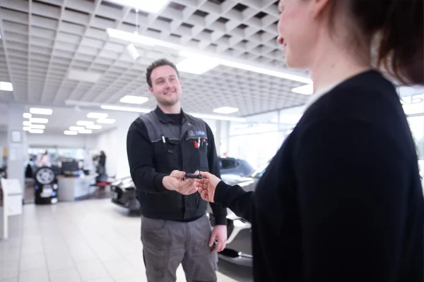 Kfz-Mechatroniker des Autohauses Hempel in Braunschweig übergibt einer Kundin ihren Autoschlüssel im Showroom.